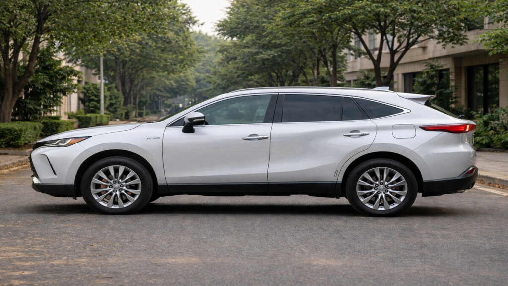 White Toyota Venza hybrid SUV side profile parked on a quiet residential street in natural daylight.
